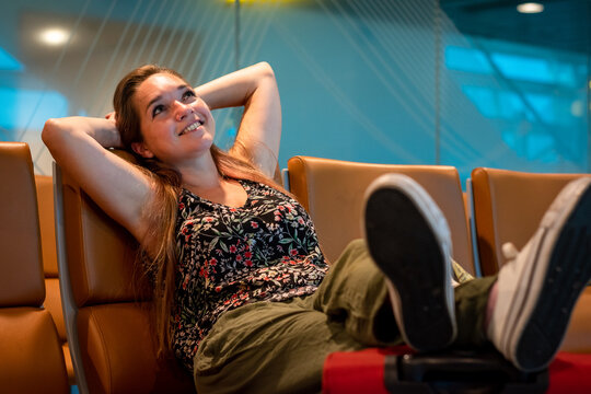 Mujer sonriente, de vacaciones en zona de embarque esperando su pr&oacute;ximo vuelo	