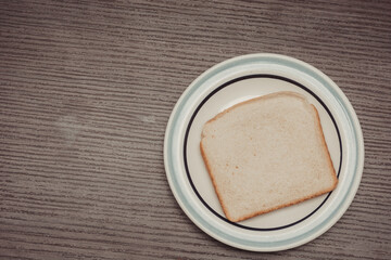 Sliced ​​white bread on porcelain plate on isolated wooden background