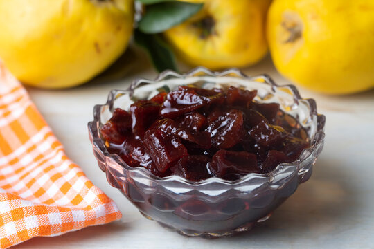 Homemade quince jam in a glass jar on an old wooden background. Fresh quince fruits and leaves and quince jam. (Turkish name; ayva receli)