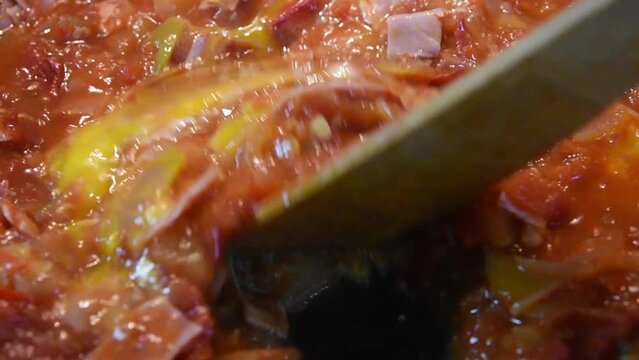 mixing the egg into the vegetable mixture. cooking lecho