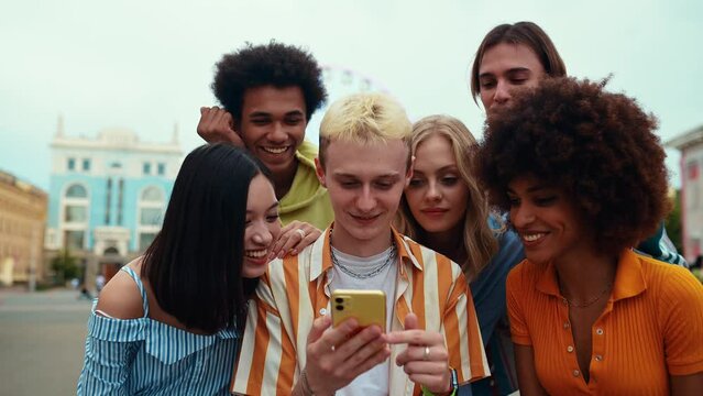 Multiethnic group of friends going out after school and having fun. Staying connected using technology and showing funny stuff online