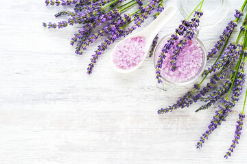 Lavender bath salt and lavender flowers on wooden background. Spa, skincare concept. Selective focus