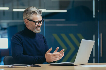 senior mature gray-haired man using laptop remote communication business meeting experienced businessman in glasses working modern office investor smiling talking colleagues.