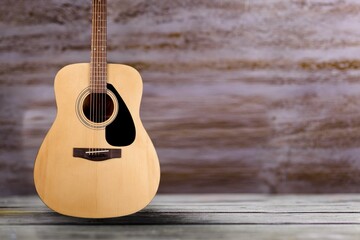 Acoustic guitar resting against a wall background
