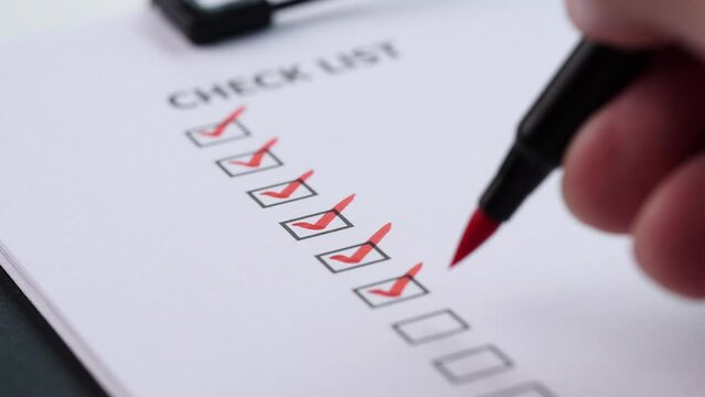 Checklist and To Do List Concept. After finishing a job on white paper, a close-up businessman ticks off or marks it with red mark on checklist, checkbox, to-do list box. selective focus 4K