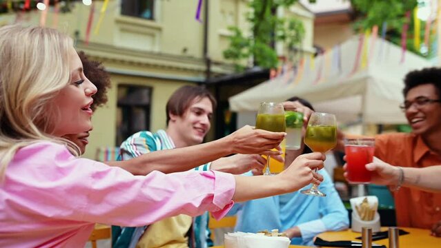 Multiethnic group of friends going out after school and having fun. Celebrating with aperitif cocktails and food in a nice bar