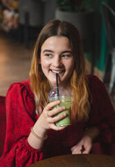 A young woman in a cafe drinks a green drink ice latte.