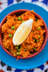 Arroz rojo, a traditional Spanish rice dish also called Mexican Red Rice made of  rice, tomatoes, green peas served in tapas bowl with lemon wegde in a Spain bodega bar