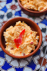 Smoked paprika tomato cream cheese spread served in terra cotta tapas bowl on colorfoul tile table...