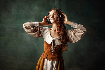 Young beautiful redhair girl with long curly hair like girl of renaissance eras isolated on dark...