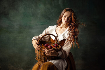 Vintage style. Young charming redhair girl with long curly hair like girl of renaissance eras isolated on dark background. Eras comparison, beauty, art, painting