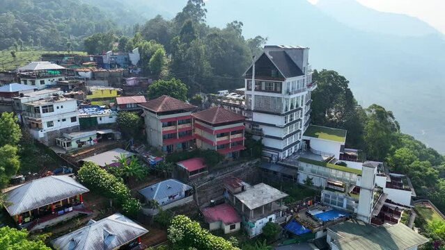 Aerial Forward Shot Of Houses Amidst Green Trees On Mountain During Sunny Day - Munnar, Kerala