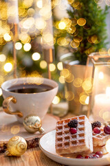 Fototapeta na wymiar Lifestyle. A cup of tea, a Christmas tree, candles and golden balls on a wooden table against a beautiful bokeh background during the Christmas holidays. Still-life. The concept of home warmth,comfort