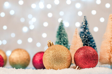 Blurred Christmas or New Year background. Christmas balls on the background of Christmas trees and blurry lights of garlands. Christmas card