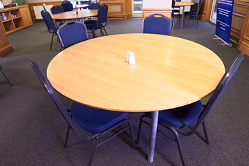 Adventure sports centre canteen dining hall with round wooden tables and blue chairs