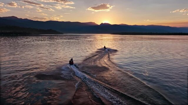 Following people riding on personal watercraft from aerial view during sunset on Hebgen Lake in Montana.
