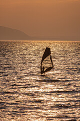 Lonely silhouette of a windsurfer on the water surface
