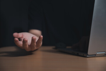 Male empty hand open palm up over computer laptop on dark background.