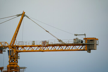 Construction crane against the blue sky and the houses under construction