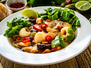 Yunnan hot pot - chinese soup with chicken meat on wooden table
