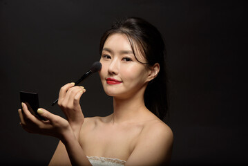 Fototapeta premium Beautiful woman applying spray water on face on neutral background