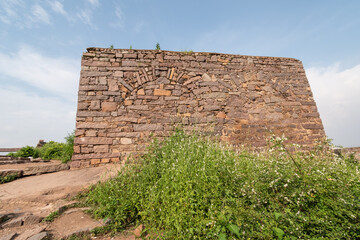 The overgrown ruins of a stone wall in the ancient historic Golconda fort in the city of Hyderabad.
