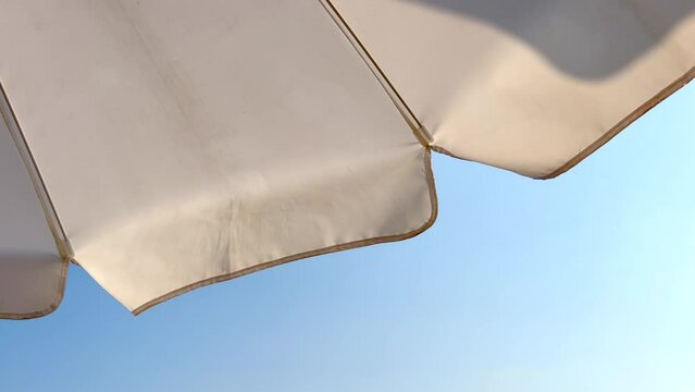 Beach umbrella seen from below in the blue sky. Looking up from the bottom