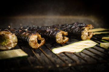 Grilled mackerel fish with the addition of herbs on the grill, close up view