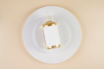 mock-up of a transparent bottle with liquid cosmetics and empty label on white round podiums on beige colored background, top view
