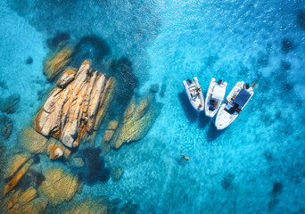 Aerial view of beautiful boats and stones in blue sea at sunset in summer. Sardinia island, Italy....