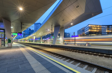 High speed train in motion on the railway station at night. Moving red modern intercity passenger...
