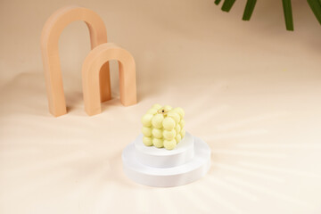 Pale green bubble candle burning on two white round podiums in peach colored arched doors for...