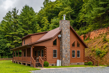 Log cabin. Wooden home. House exterior. Log cabin in Great Smoky Mountains North Carolina. Scenic view. Great for vacation. Country landscape with cottage. Green forest on background. Pine trees. - Powered by Adobe