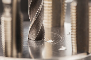 metal drill bit make holes in aluminum billet on industrial drilling machine with shavings. Metal...