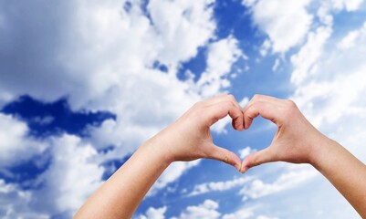 Human hands in the form of heart against the sky. Hands in shape of love heart. Love, friendship...