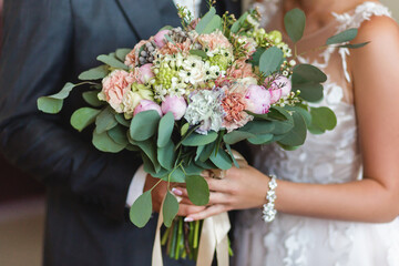 bride holding a bouquet of flowers in her hand, the groom embracing her