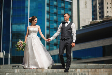 Newlyweds in love hug on the background of a building with windows on the street in the city.