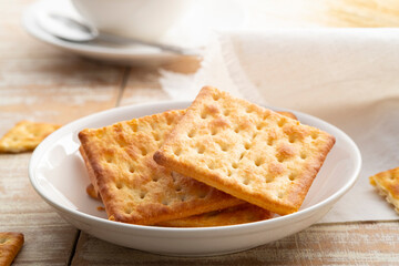 Dry thin crispy crackers in white plate on wood table