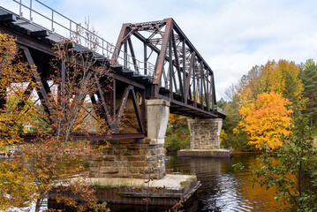 Fototapeta na wymiar Old metal railroad bridge spanning a river on a cloudy autumn day