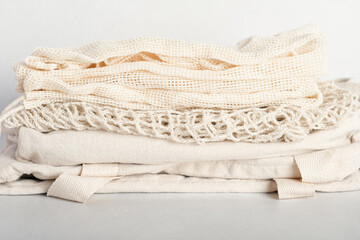 stack of eco friendly bags on a grey background. String and canvas bags made of cotton threads. Zero waste lifestyle. eco shoppers. reusable sustainalbe shopping.
