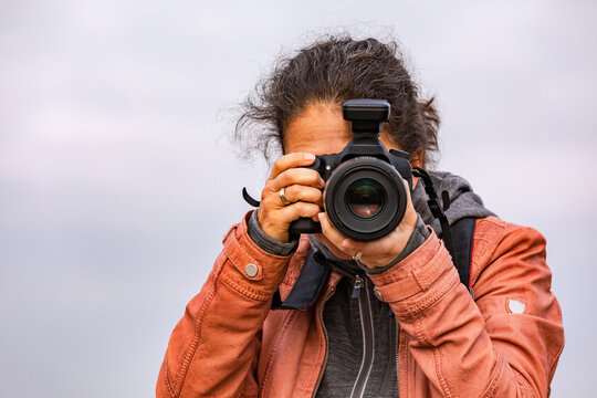 Front view of a woman with a professional DSLR camera taking a picture