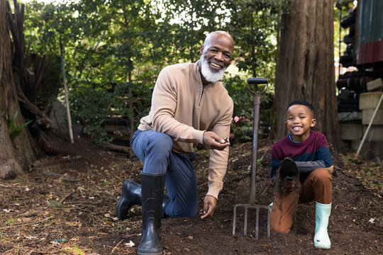 Portrait of happy senior african american man with his grandson in garden