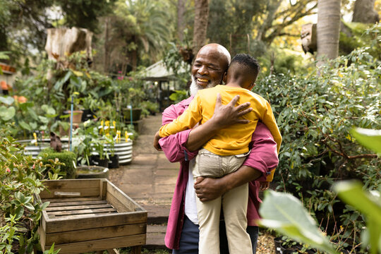Happy senior african american man with his grandson embracing in garden
