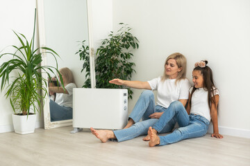 Family warming near electric heater at home.