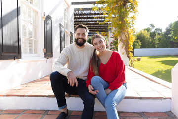 Portrait of happy caucasian couple sitting on terrace in garden, smiling to camera