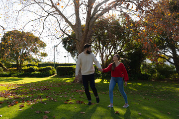 Fototapeta premium Happy caucasian couple walking in garden holding hands and talking