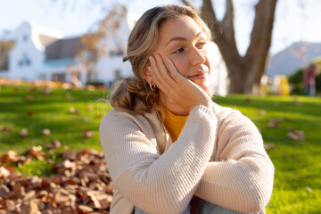 Happy caucasian woman smiling and looking away, sitting in garden