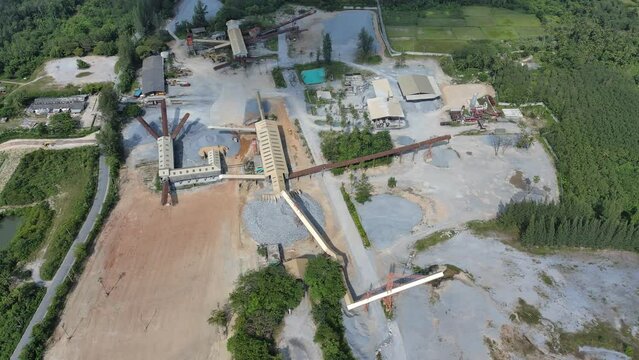 4k aerial view of stone factory with working gravel crushe and heavy construction machine equipment in quarry, rock industry business work for manufacture gravel, dust pollution to dirty environment