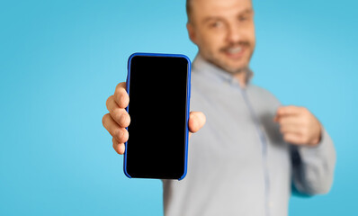 Man Advertising Mobile Offer Showing Smartphone Screen On Blue Background