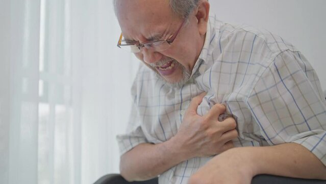 Asian senior man suffering from heart attack. Male patient on wheelchair has difficulty breath and having chest pain.